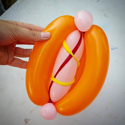 A hot dog made from orange, pink, red and yellow modelling balloons