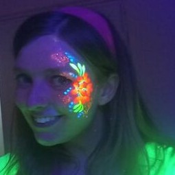 Woman smiling with neon flower face paint glowing under UV light